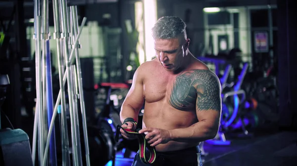 A man bodybuilder with tattoo binding his wrists — Stock Photo, Image