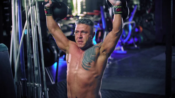 A shirtless man bodybuilder performing lifting heavy kettlebells — Stock Photo, Image