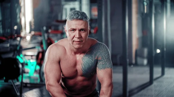 Hombre duro con el pelo gris sentado en el gimnasio —  Fotos de Stock