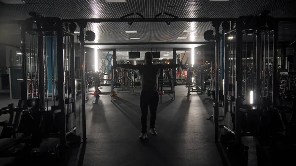 Silhouette of tough man training in the dark gym — Stock Photo, Image