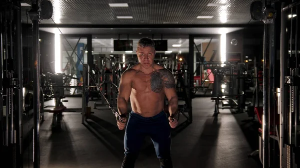 Жорсткий чоловік з сірим волоссям та татуюванням на плечі тренує руки в спортзалі — стокове фото