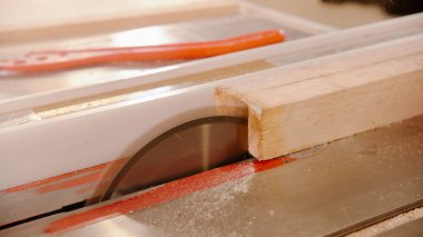 Dairesel testere kullanarak odunları kesiyor.