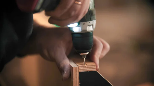 Tesařský průmysl - dělník vrtá šroub do dřevěné desky — Stock fotografie