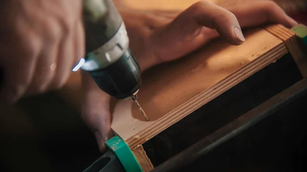 Carpintería - el hombre taladra agujeros en la pieza de madera contrachapada — Foto de Stock