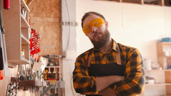 Uomo barbuto lavoratore in camicia gialla in piedi in officina — Foto Stock