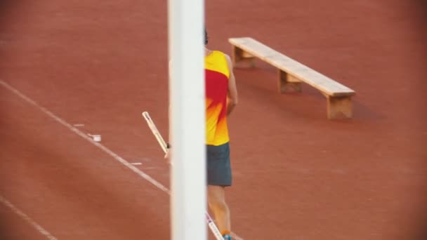 Pole vault training - an athletic man walking on the track holding his pole — Stock Video