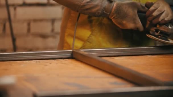 Mannen arbetare slipning sömmarna av en järnram i verkstaden - gnistrar — Stockvideo
