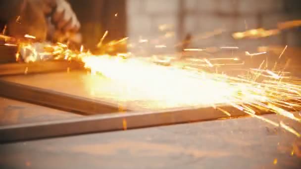 Man worker grinding the seams of a metal frame in the workshop — Stock Video