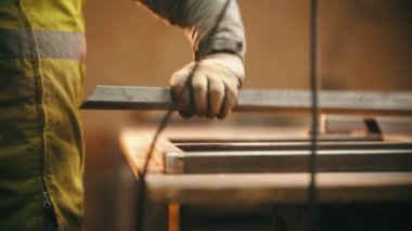 Kaynak atölyesinde çalışıyorum. Metal kirişin kesimini öğütüyorum.