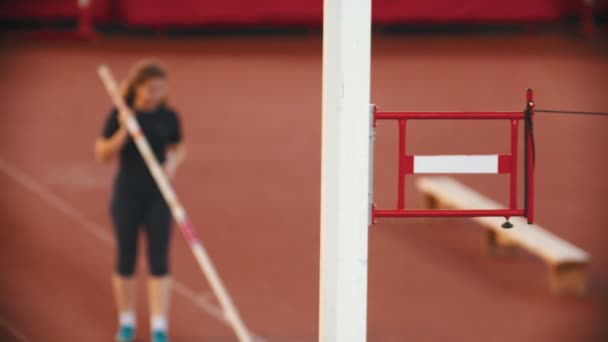 Тренировка прыжков с шестом на стадионе - монтажная стойка - женщина машет рукой на заднем плане — стоковое видео