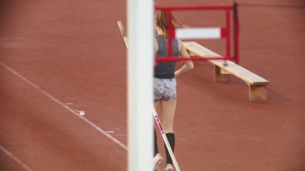 Entrenamiento de bóveda de poste en el estadio - mujer joven con el pelo largo corriendo en la pista — Vídeos de Stock