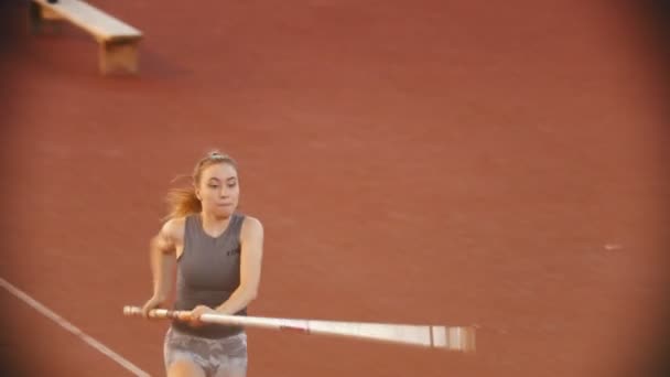 Entraînement de saut à la perche sur le stade - jeune femme aux cheveux longs sautant par-dessus le bar — Video