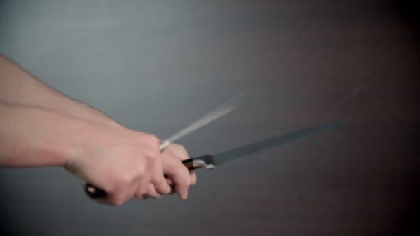 Una persona afilando cuchillos entre sí en el interior — Vídeo de stock