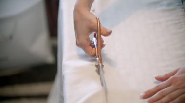 Genç bayan terzi izi takip ederek kumaşı kesiyor.