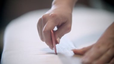 Genç bayan terzi kumaşı sabun ve cetvelle keserek iz bırakıyor.