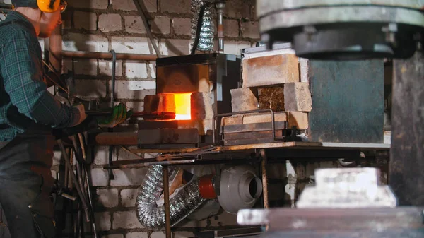Praca kowala - wkładanie dłuższego kawałka metalu do pieca — Zdjęcie stockowe