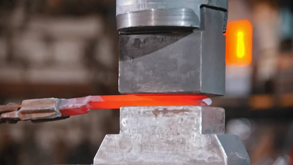 Forjar um objeto a partir de um pedaço de metal mais longo vermelho quente usando uma máquina de pressão — Fotografia de Stock