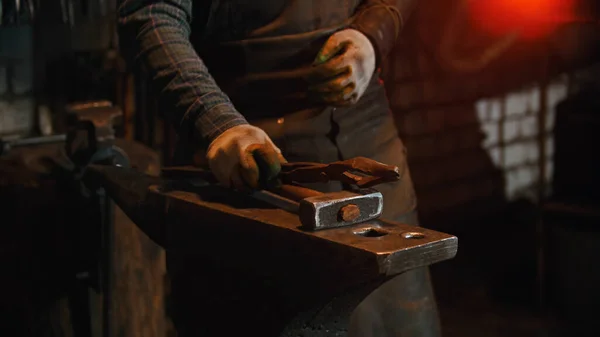 Forging industry - a man blacksmith putting his instruments on the anvil