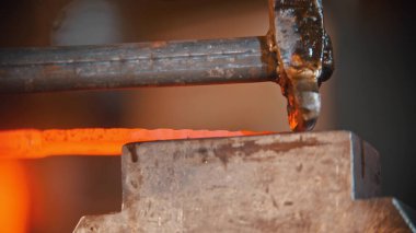 Demirci, demircilik makinesinin baskısına daha uzun ve parlak bir metal parçası yerleştirdi.