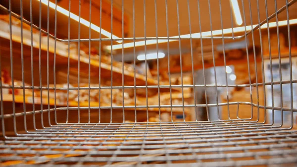 an empty grocery trolley in the supermarket near the department with bakery