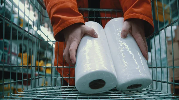 Мужчина покупает туалетную бумагу и кладет ее в тележку с продуктами — стоковое фото