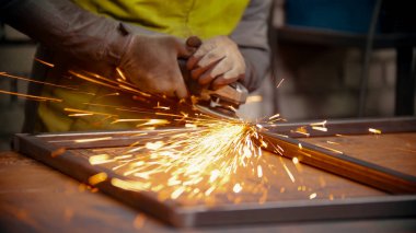 Metal bir çerçevenin dikişleri öğütülmüş. Metalden kıvılcımlar çıkıyor.