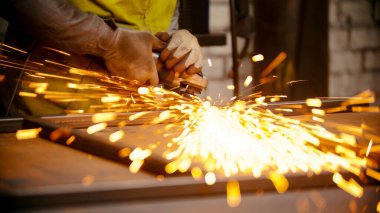 Metal çerçevenin dikişlerini öğüten işçiler - metalden parlak kıvılcımlar çıkıyor