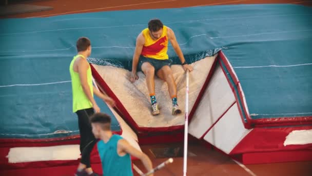 Трое спортсменов на тренировке по прыжкам с шестом на стадионе — стоковое видео