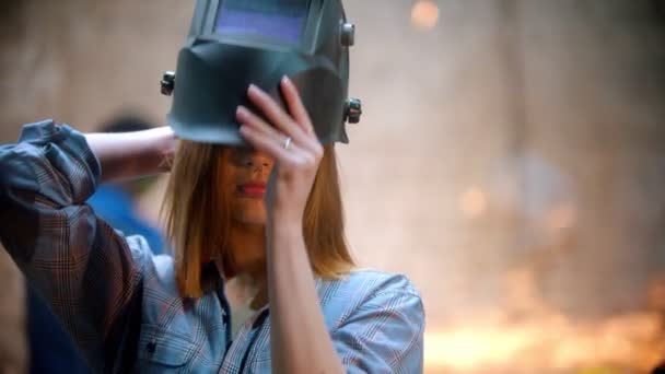 Молодая сексуальная женщина, стоящая в мастерской и надевающая защитный шлем — стоковое видео