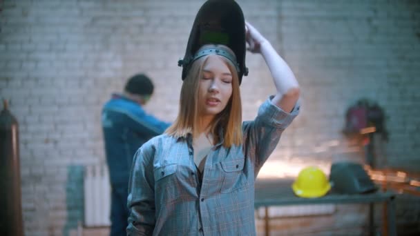 Молода сексуальна жінка позує в майстерні, тримаючи кутову шліфувальну машину — стокове відео
