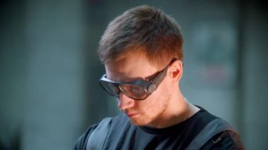 Genç yakışıklı adam koruyucu gözlüklerle öğütme atölyesinde çalışıyor.