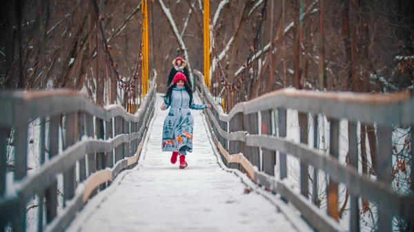 Zwei bunte Frauen laufen auf der schneebedeckten Brücke und haben Spaß — Stockfoto