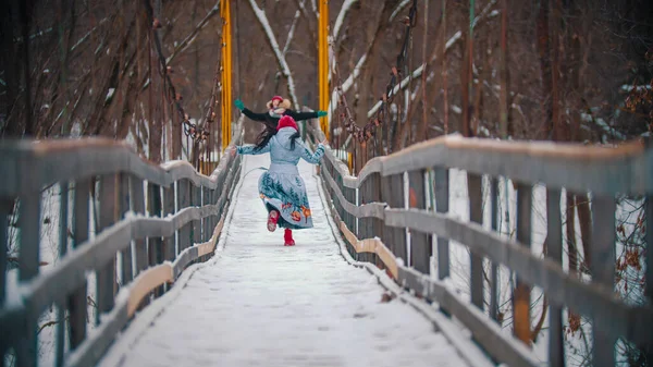 Zwei Frauen rennen auf der verschneiten Brücke und haben Spaß — Stockfoto