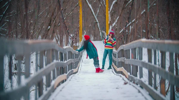 Twee kleurrijke jonge vrouwen maken foto 's op besneeuwde brug — Stockfoto