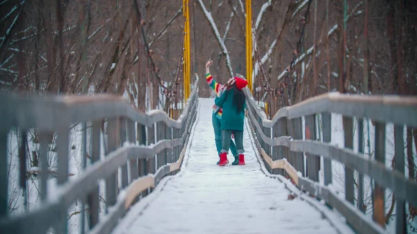 2人のカラフルな若い女性が冬の橋で写真を撮る — ストック写真