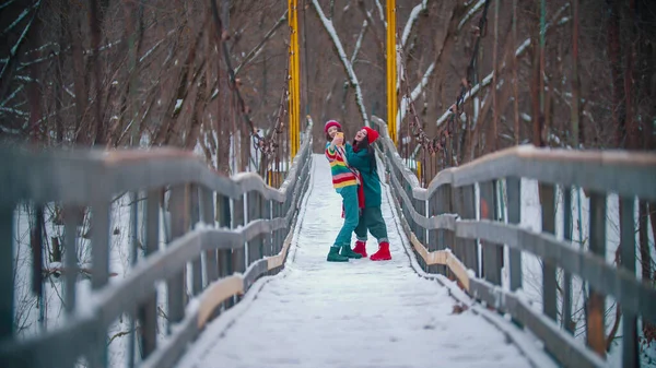2人のカラフルな若い幸せな女性が冬の橋で写真を撮る — ストック写真