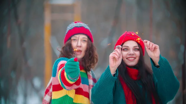 Jóvenes mujeres sonrientes de pie en el puente de invierno sosteniendo bengalas — Foto de Stock