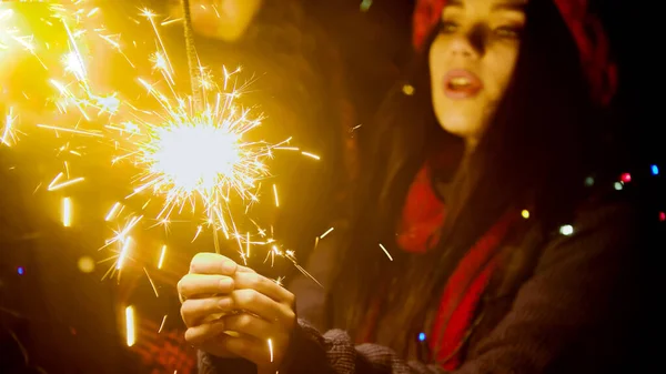 Young pretty woman holding sparklers at night — Stock Photo, Image