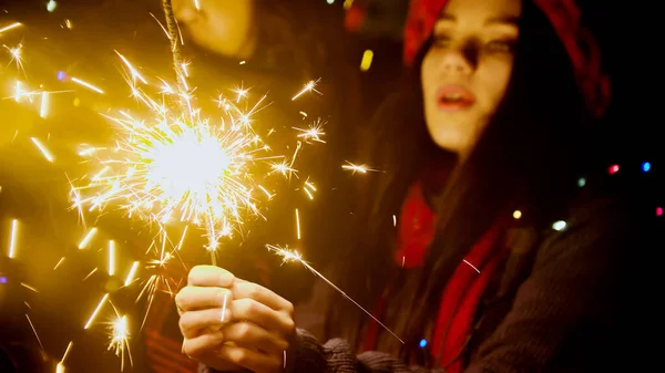 Young pretty woman holding bright sparkler at night — Stock Photo, Image