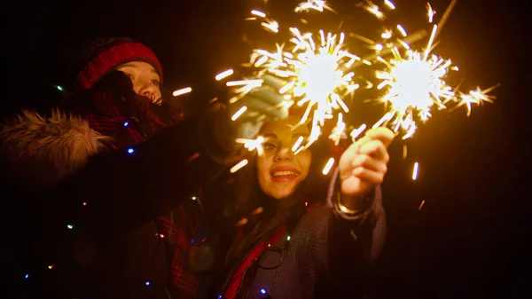 Smiling women friends holding bright sparklers at night outdoors — Stock Photo, Image