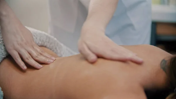 Zabieg masażu - mistrz masażu masaż kobiet z powrotem z tatuażem przy użyciu olejku do masażu — Zdjęcie stockowe