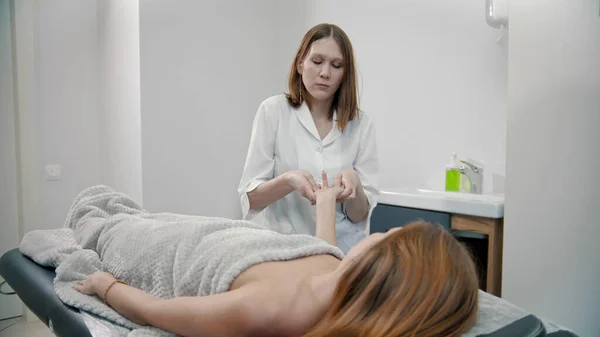 Terapeuta dando un masaje para las palmas y los dedos de una mujer joven —  Fotos de Stock