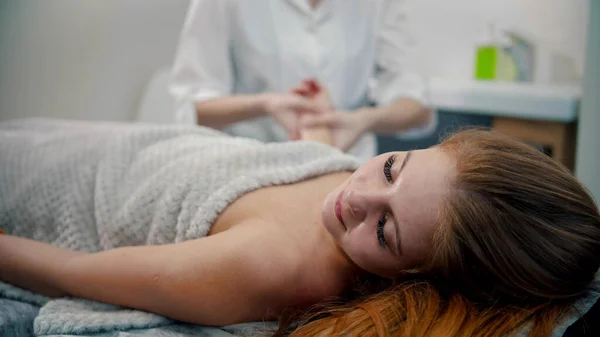 Massagem - jovem massagista massagista massageando as mãos de sua cliente mulher — Fotografia de Stock