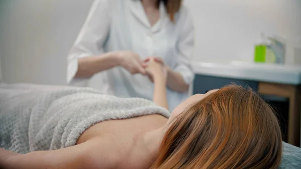 Kvinnlig ung massage terapeut massera händer kvinnlig klient — Stockfoto