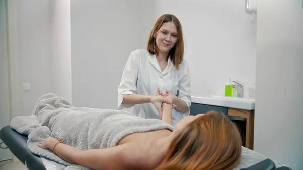 Jovem massagista massagista massageando pulso de cliente mulher — Fotografia de Stock