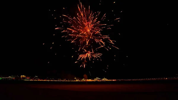 Red fireworks explode late at night on the street