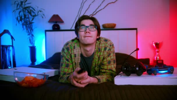 Junger schöner Mann liegt auf dem Bett vor dem Fernseher — Stockvideo