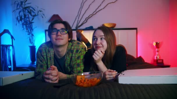 Jovem casal bonito assistindo filme deitado na cama juntos — Vídeo de Stock