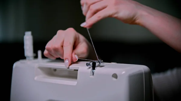 女裁缝的手在缝纫机上放了一根线 — 图库照片