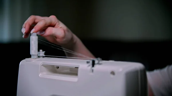 Mão de costureira mulher define uma meada de linha na máquina de costura dentro de casa — Fotografia de Stock